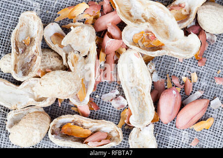 Gebrochen und Erdnüsse mit Muscheln, essbare Teil ohne Schalen und für den Verzehr fertig geschält, liegt ein Bettwäsche Tischdecke in der Küche Stockfoto