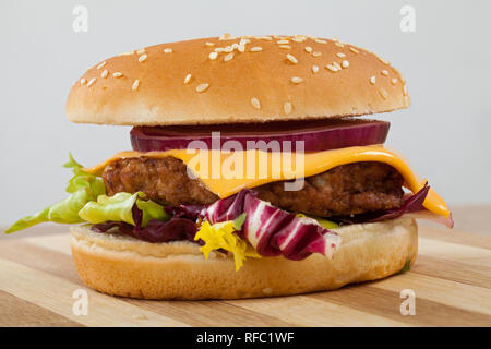 In der Nähe Bild von einem leckeren Cheeseburger mit Rindfleisch, Cheddar, Salat in einem sesambrötchen Stockfoto