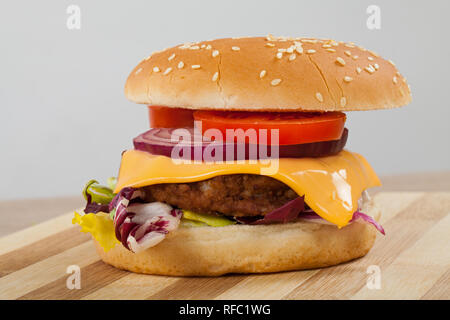 In der Nähe Bild von einem leckeren Cheeseburger mit Rindfleisch, Cheddar, Salat in einem sesambrötchen Stockfoto