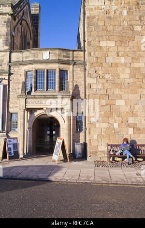 Student sitzt außerhalb der Durham University Library auf kalten Morgen mit Laptop Durham City Winter 2018 Stockfoto