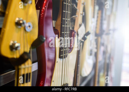 Gitarren und Bässe hängen an der Wand in einem Geschäft Stockfoto