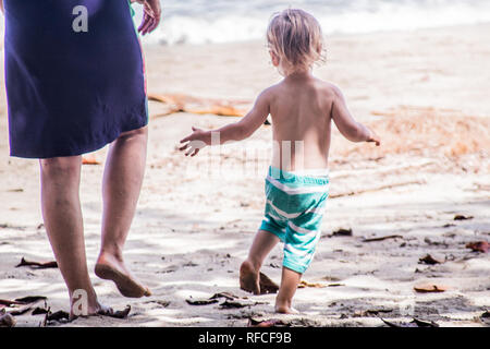 Ein Foto von einem glücklichen jungen Springen und Laufen an einem sonnigen Sandstrand Stockfoto