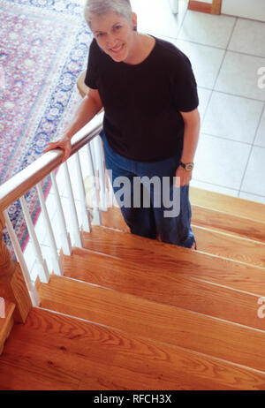 Reife Frau lächelt Kamera während Asenting Treppen zu Hause, USA Stockfoto