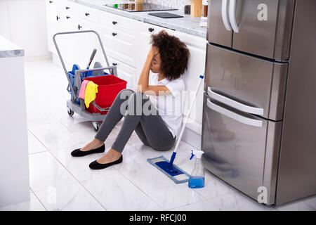 Erschöpft Afrikanische junge Frau sitzt auf dem Boden in der Küche Stockfoto
