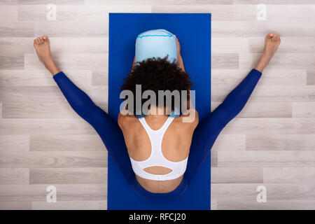 Einen Überblick über eine junge Frau sitzt auf der blauen Trainingsmatte Yoga Stockfoto