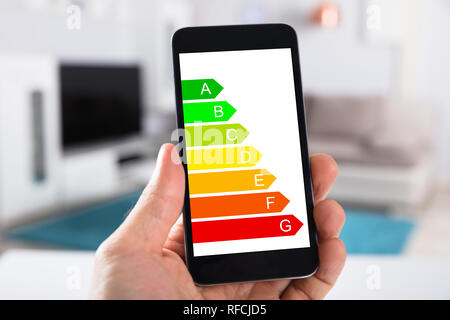 Nahaufnahme von einer Person mit Handy Übersicht Energieeffizienz Grafik auf dem Bildschirm Stockfoto