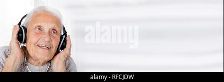 Lächelnd Senior Frau Hören von Musik über Kopfhörer Stockfoto
