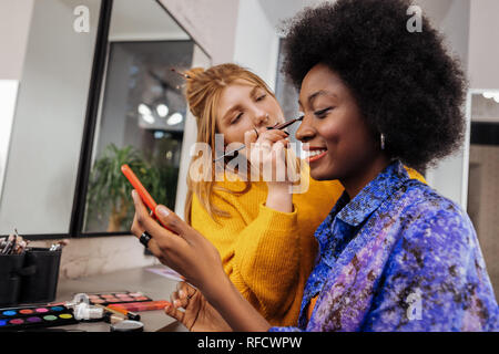 Hübsche junge stylistin in einem gelben dicken Pullover Suche inspiriert Stockfoto