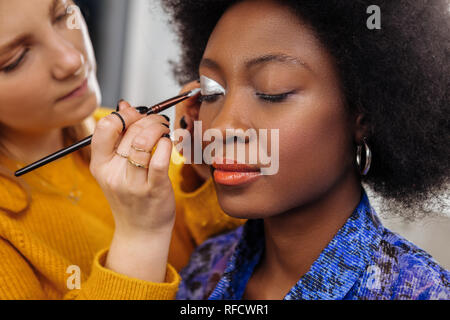 Hübsche junge stylistin in einem gelben dicken Pullover Gefühl inspiriert Stockfoto