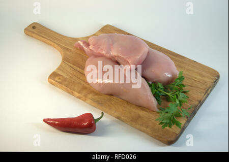 Huhn weißes Fleisch, Verrundungen, auf einem Schneidebrett mit rotem Paprika. Ein Bild auf einem weißen Hintergrund. Stockfoto
