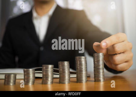 Geschäftsmann nimmt Münzen auf den Tisch und zählt Geld. Geschäftskonzept. Stockfoto