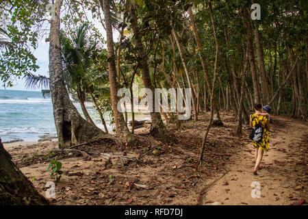 Ein Foto von einer Frau und Sohn zu Fuß auf einem Wanderweg in der Nähe zu einem schönen Strand mit türkisblauem Wasser in Manzanillo National Park, Costa Rica Stockfoto