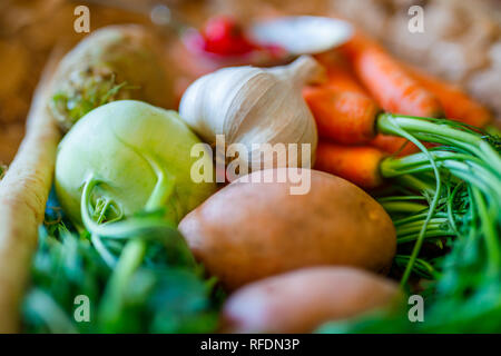 Karotten, Sellerie, Rüben, Chili und Knoblauch frisches Gemüse auf wicker Schüssel Vorbereitung für das Kochen mit verschwommenen Hintergrund Stockfoto