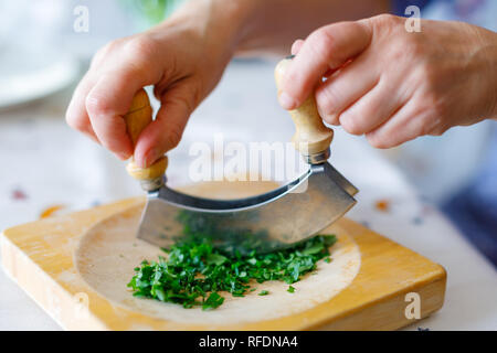 Eine Frau fetzen Petersilie auf einem hölzernen Schneidebrett in der Küche Stockfoto