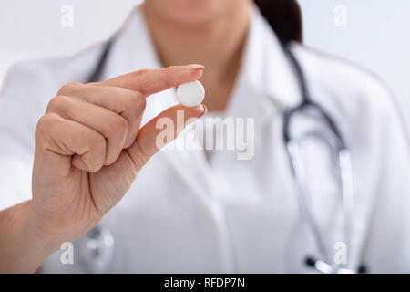 In der Nähe der weiblichen Doktor mit Stethoskop um den Hals halten weiße Tablette in der Hand Stockfoto