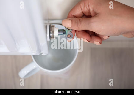 Nahaufnahme von einer Person Hand drehen Kühler Entlüftungsventil zu lösen, mit Schale Stockfoto