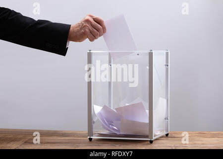 Nahaufnahme der Geschäftsmann Hand Stimmzettel in einem Glaskasten einfügen Stockfoto