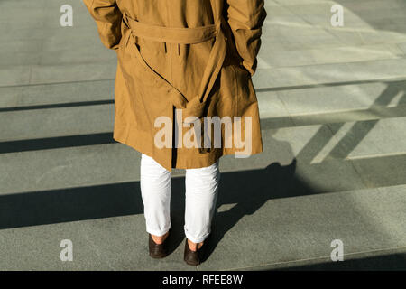 Junge Menschen stehen im Freien und das Tragen modischer Braune Jacke mit grauem Beton Hintergrund Stockfoto