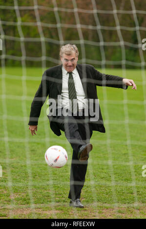 Der ehemalige englische Fußballspieler Trevor Brooking International West Ham MBE tritt einen Fußball in Richtung eines Netzes wie ein Elfmeterschießen. Stockfoto