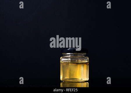 Trüffel Pilz in ein Glas Honig auf schwarzem Hintergrund. Minimalismus in der Komposition. Luxus essen. Freier Platz für Text Stockfoto