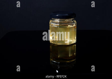 Trüffel Pilz in ein Glas Honig auf schwarzem Hintergrund. Minimalismus in der Komposition. Luxus essen. Freier Platz für Text Stockfoto