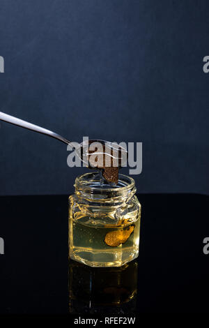 Trüffel Pilz in ein Glas Honig auf schwarzem Hintergrund. Minimalismus in der Komposition. Luxus essen. Freier Speicherplatz für Tex Stockfoto