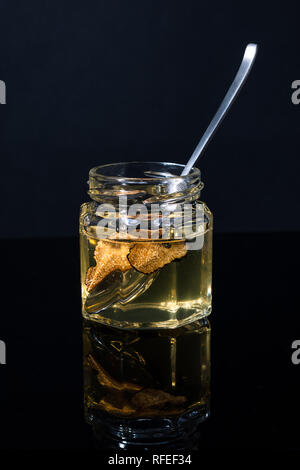 Trüffel Pilz in ein Glas Honig auf schwarzem Hintergrund. Minimalismus in der Komposition. Luxus essen. Freier Platz für Text Stockfoto