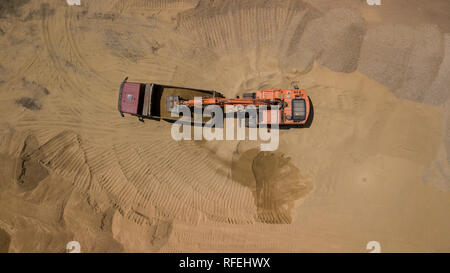 Luftbild des Baggers gießt Sand in den Wagen. Stockfoto