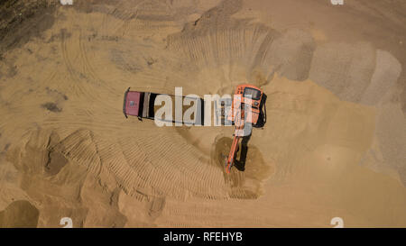 Luftbild des Baggers gießt Sand in den Wagen. Stockfoto