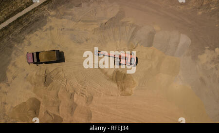 Luftbild des Baggers gießt Sand in den Wagen. Stockfoto