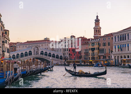 Rialto Brücke (Ponte de Rialto) über den Canal Grande bei Sonnenaufgang/Sonnenuntergang mit Gondel, Venedig, Italien Stockfoto