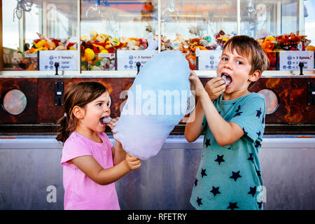 Foto von einem Bruder und Schwester essen eine grosse Zuckerwatte in einem Vergnügungspark. Stockfoto
