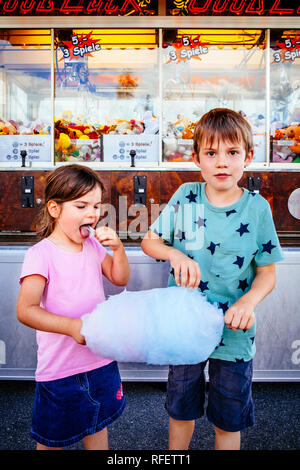 Foto von einem Bruder und Schwester essen eine grosse Zuckerwatte in einem Vergnügungspark. Stockfoto