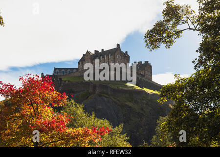 Das Edinburgh Castle, wie von der Princes Street gesehen an einem sonnigen Herbsttag mit bunten Bäumen und blauer Himmel (Edinburgh, Schottland, Großbritannien, Europa) Stockfoto