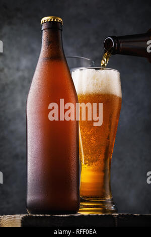 Flasche, ein Bier und ein Glas trinken auf einem Holztisch. Alkoholische still life close-up Stockfoto