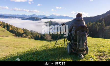 Mann auf Rollstuhl Fotos von schönen Landschaft in einer nebligen Morgen, St. Thomas, Slowenien Stockfoto