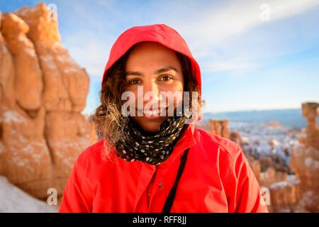 Portrait von eine hübsche junge Frau im Winter Kleidung vor Felsnadeln, Winter, Rim Trail, Bryce Canyon National Park, Utah Stockfoto