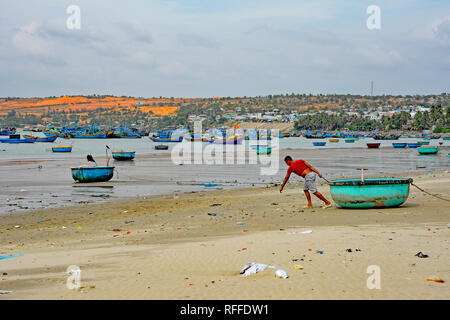 Mui Ne, Vietnam - 27. Dezember 2017. Ein Fischer Hols seine traditionelle runde Boot in Richtung Meer. Obwohl es eine große Touristenattraktion in der Gegend Stockfoto