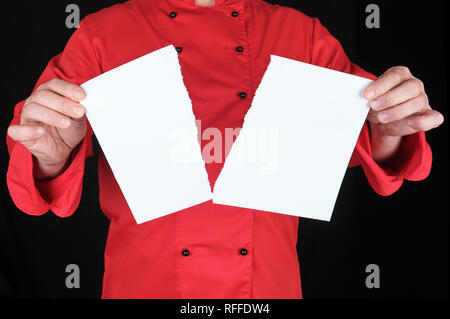 Mann in einem roten Uniform hält ein weißes Blatt Papier zur Hälfte abgerissen, schwarzer Hintergrund Stockfoto