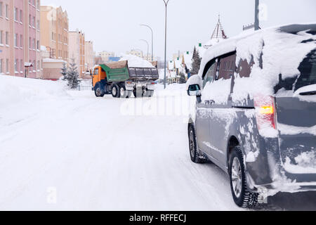 Closeup grau Minibus schmutziges Auto mit Schnee auf der Stadt abgedeckt. Von der Seite. Konzept, Schnee, Schneefall, schlecht nördlichen Wetterbedingungen, niedrig Stockfoto