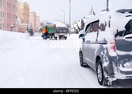 Closeup grau Minibus schmutziges Auto mit Schnee auf der Stadt abgedeckt. Von der Seite. Konzept, Schnee, Schneefall, schlecht nördlichen Wetterbedingungen, niedrig Stockfoto