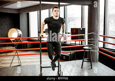 Jungen athletischen Mann ziehen an der Bar Aufwärmen vor dem Training auf den Boxring in der Turnhalle Stockfoto