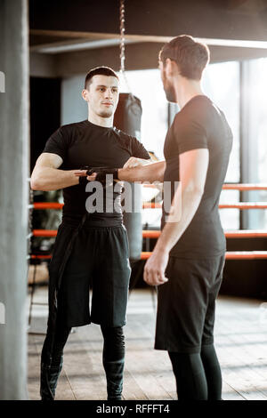 Wicklung bandage Boxing Trainer am Handgelenk für einen Mann, der Vorbereitung auf die Boxen auf den Boxring in der Turnhalle Stockfoto