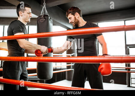 Boxing Trainer helfende Hand zu entspannen, um Verletzungen zu vermeiden, während das boxtraining in der Turnhalle Stockfoto