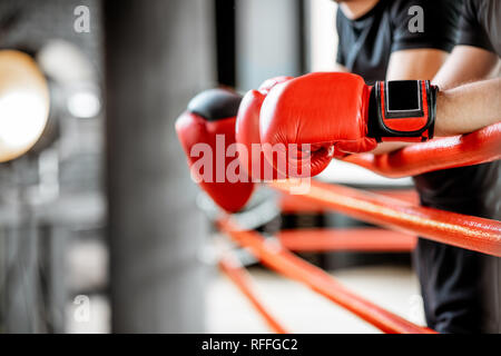 Boxer ruht auf dem Boxring, Nahaufnahme auf die Boxhandschuhe an den Seilen Stockfoto