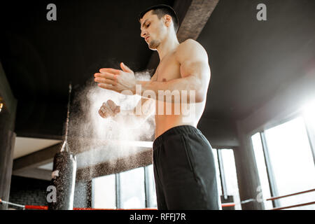 Athletischer mann Händeklatschen mit Talkum, Vorbereitung für das Training im Fitnessstudio Stockfoto