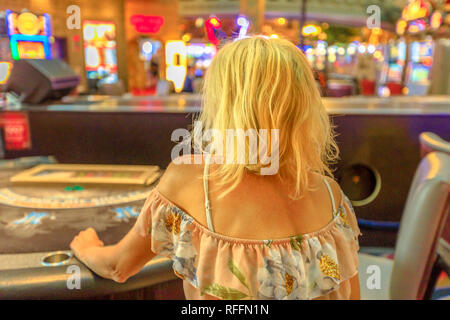 Kaukasische blonde Frau spielen im Casino bei Blackjack Tisch sitzen. Spieler süchtiger Konzept. Lifestyle Mädchen spielen im Casino in Las Vegas, Nevada Stockfoto