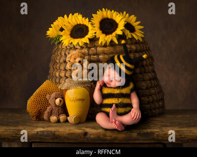 Sleepy Cute Baby in Biene outfit Gleitstift gegen ein antiker Bienenstock Stockfoto