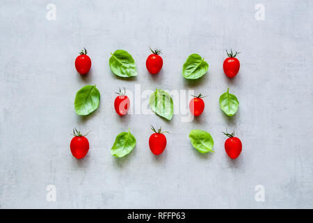 Kreative Gestaltung mit frischen Tomaten und Basilikum Blätter auf hellen Hintergrund der Ansicht von oben. Zutaten für gesundes Kochen. Essen Konzept. Flach Stockfoto