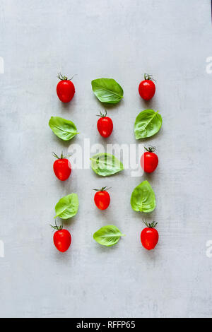 Zutaten für gesundes Kochen flach. Kreative Gestaltung aus Cherry Tomaten und Basilikum Blätter auf hellen Hintergrund. Essen Konzept. Ansicht von oben Stockfoto
